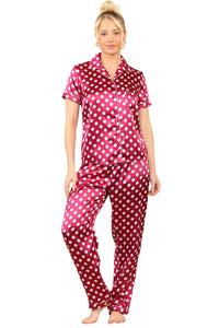 Model wearing a fuchsia satin polka dot pyjama set featuring a short-sleeve button-up top and matching full-length pants, showcasing a stylish and comfortable loungewear option.