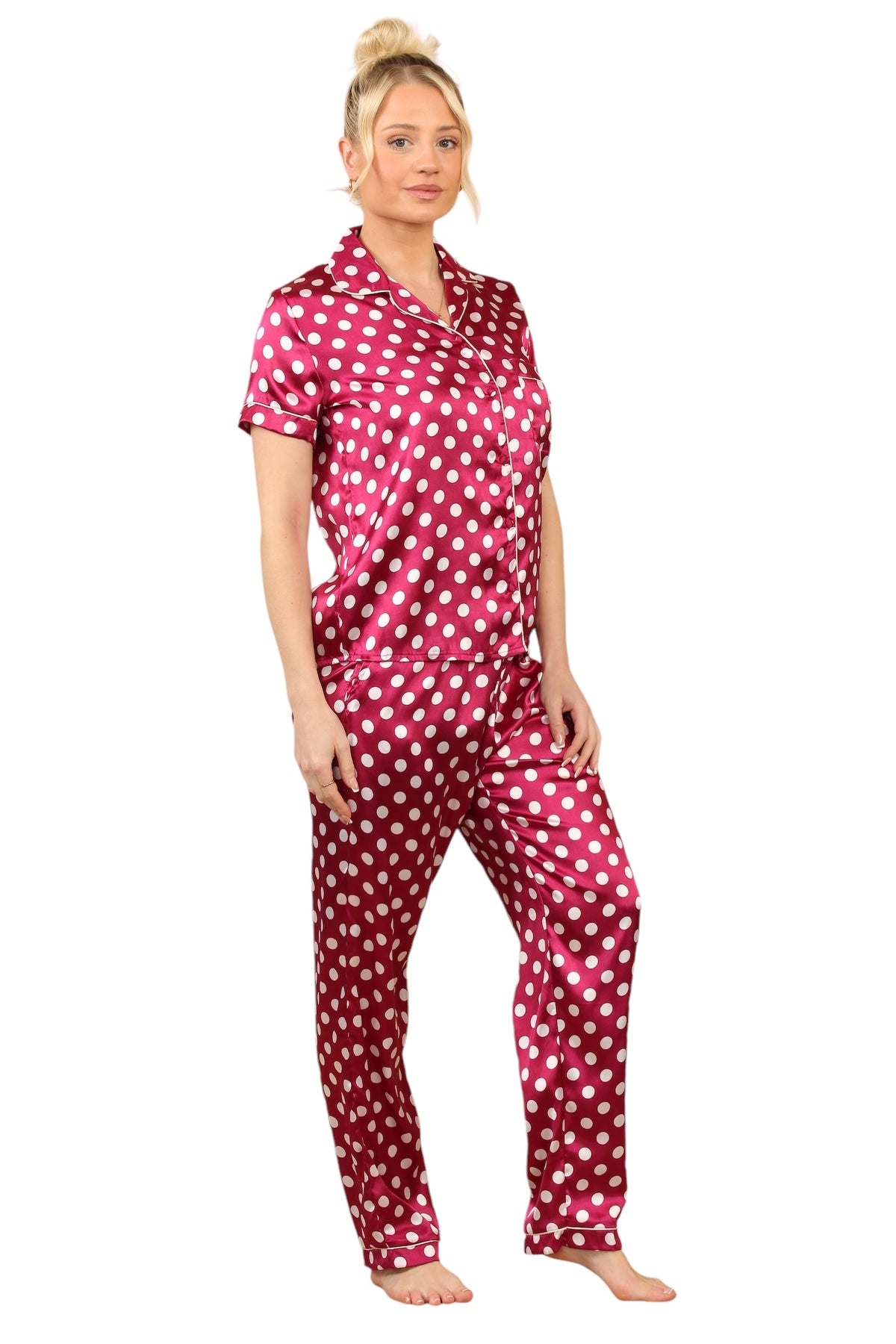 Model wearing a fuchsia satin polka dot pyjama set featuring a short-sleeve button-up top and matching full-length pants, showcasing a stylish and comfortable loungewear option.