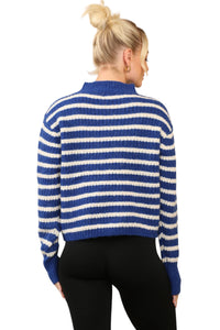 Model wearing a cosy blue and cream striped jumper with a mock neck, long sleeves, and a relaxed fit. The jumper is made of soft acrylic 