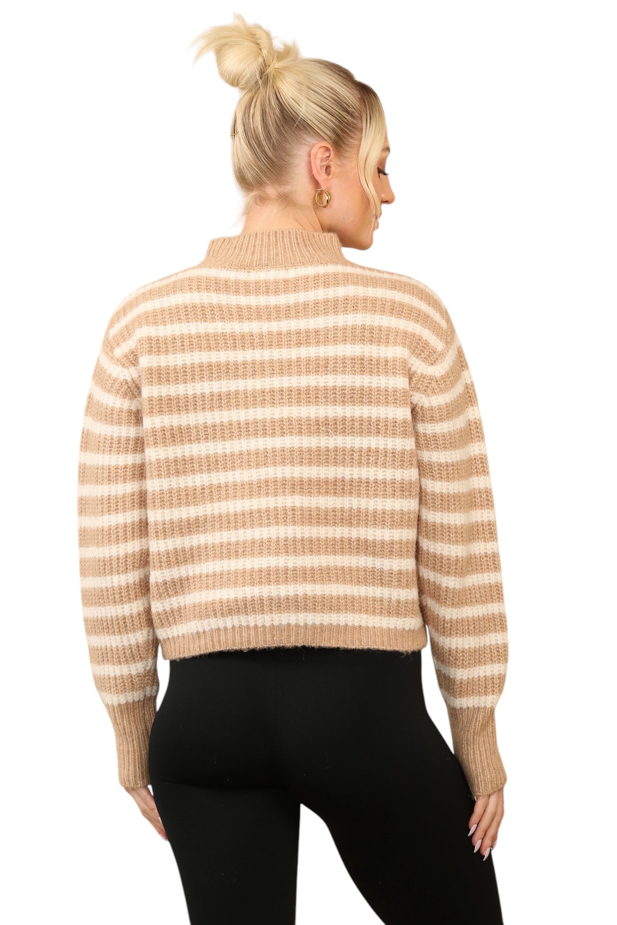 Model wearing a cosy beige and cream striped jumper with a mock neck, long sleeves, and a relaxed fit. The jumper is made of soft acrylic and styled with black leggings