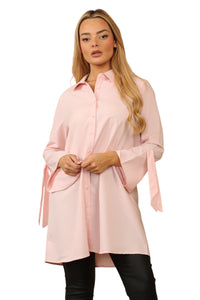 Model wearing a pastel pink, long-sleeve blouse with a collared neckline, button-through front, and tie-cuff sleeve detail, crafted from 100% polyester