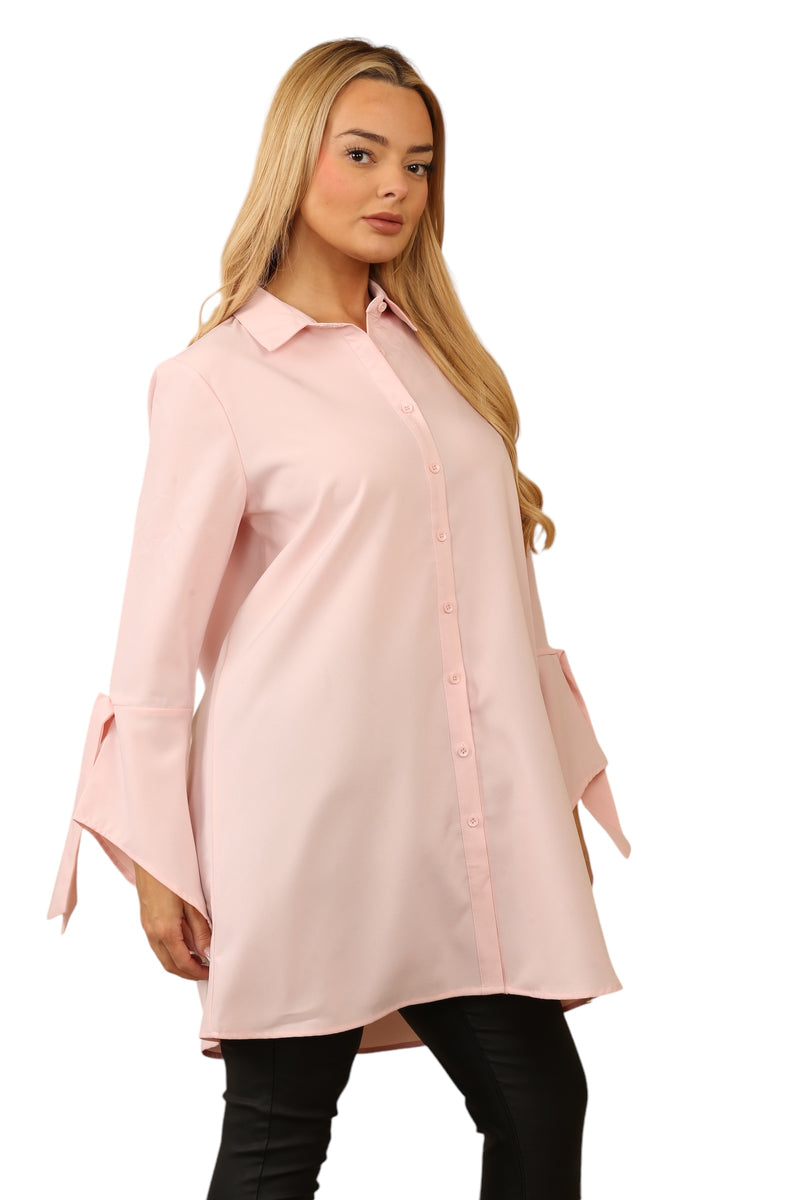 Model wearing a pastel pink, long-sleeve blouse with a collared neckline, button-through front, and tie-cuff sleeve detail, crafted from 100% polyester