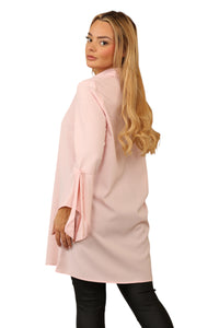 Model wearing a pastel pink, long-sleeve blouse with a collared neckline, button-through front, and tie-cuff sleeve detail, crafted from 100% polyester